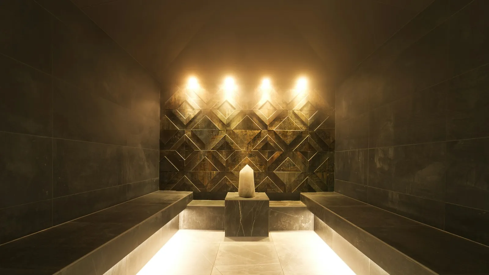 A warmly lit stone steam room with a single candle